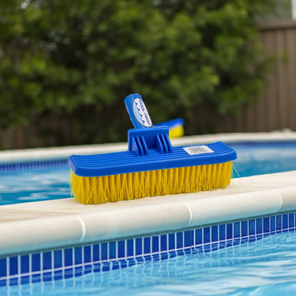 big al brush with blue handle and yellow bristles on a pool ledge.
